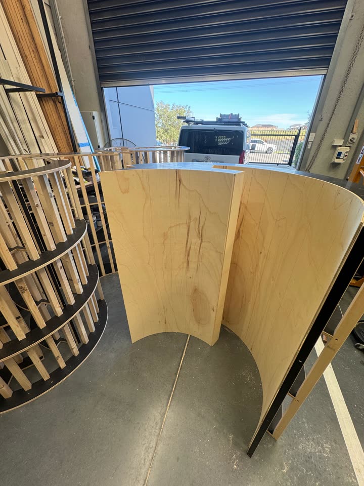 Round column frames made from stacked ring plates and vertical battens, assembled in the workshop.
